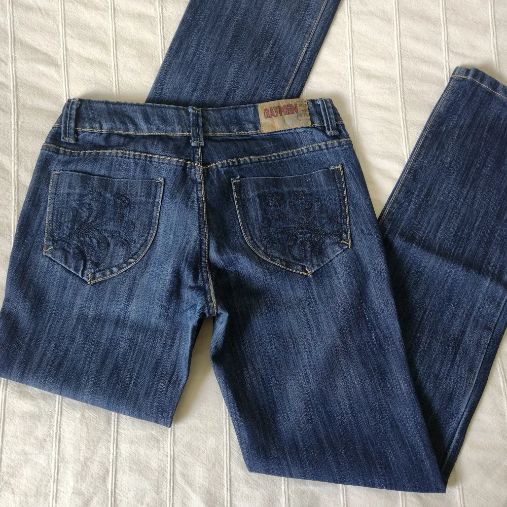 Skitsnygga y2k jeans som är raka/något utsvängda i modellen. Låg/medelhög midja. Brodyr på bakfickor och lilla fickan i fram, och en del slitningar. I fint skick. 95% bomull. Storlek 42 - innerbenslängd ca 84 cm, midja ca 40 cm mätt tvärs över.. Jeans & Byxor.