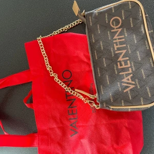 Valentino Väska - Liten valentino axelväska. Kort band samt långt läderaxelband medföljer samt dustbag. Sparsamt använd🩷