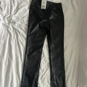 Oanvända skinnbyxor från Zara - Aldrig använt pga för små. Fina svarta byxor i skinnimitation. Dragkedja i midjan och nertill. 