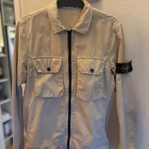 Stone island overshirt S - Stone island overshirt i en ljus Biege färg. Köpt på stone island i Stockholm.  Endast använd ett fåtal gånger och är i princip nyskick.  Vid eventuella frågor är det bara att höra av sig, Med vänlig hälsning, Gustav Brånfelt