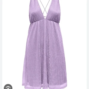 Lila glittrig klänning - Jättefin lila glittrig klänning. Testad men inte använd. Klänningen är kort och v-ringad. Banden är knytbara och ryggen är öppen Jättefint material och har en så fin färg med fint skimmer💕 Köpt för 450, produkten säljs inte längre