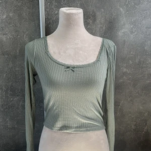 Söt croppad longsleeve - En grön croppad longsleeve med en lite fyrkantig urringning med spets, och liten rosett.  Har inte använt den mycket och den är i bra skick. :) Skriv för mer information 💞