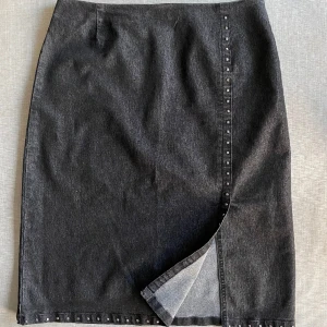 Jeanskjol - Knälång kjol. Sparsamt använd, i nyskick. Slit på sidan och nitdetaljer kring kanten. 