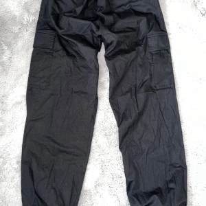 Cargobyxor - Populära baggy byxor som går att justera uppe och nere vid benen. Fickor vid sidorna samt längst benen. Orättvist ljus på bilderna. Byxorna är i mörk svart. Passar XS-L