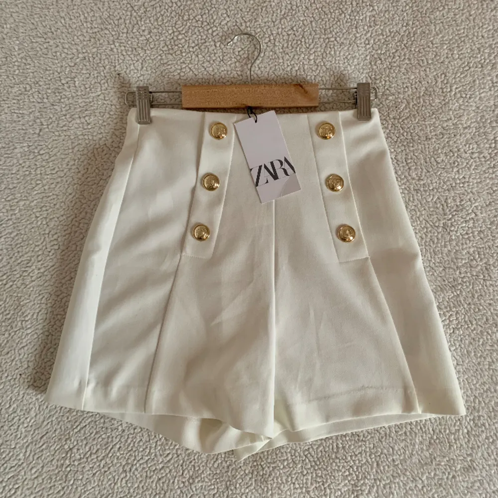 Otroligt stiliga högmidjade vita shorts från ZARA med guldknappar. Nya med tags. Utan anmärkningar.. Shorts.