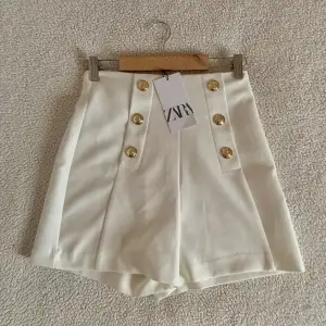 Otroligt stiliga högmidjade vita shorts från ZARA med guldknappar. Nya med tags. Utan anmärkningar.