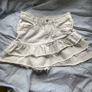 Jeanskjol - Vit volangjeanskjol från Gina Tricot i superfint skick. Säljer pga att den inte kom till användning. Använd ca 2 gånger. Finns inga fläckar eller tecken på användning. Priset kan diskuteras! Kjolen är i storlek 34 men passar mig som har 36