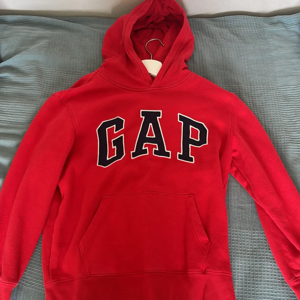 En röd hoodie från GAP med stor logotyp på framsidan. Tröjan har en känguruficka och en huva. Tillverkad av en blandning av bomull och polyester. Jag köpte den för 500kr så säljer den nu för 200kr. Tröjor & Koftor.