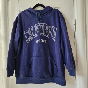Hoodie - Mörkblå hoodie med tryck. I mysigt och varmt material. Något oversized och lång i modellen. 