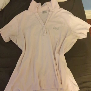 Ljusrosa tshirt med rhinestone rosette - Jättegullig ljusrosa tshirt med en rhinestones rosette. Passar perfekt till sommaren. Är storlek XL men passar även S/L/M! Har inte använt så mycket men säljer för att den inte passar mig. I bra skick!