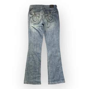 jättefina true religion jeans. dem är lågmidjade och flared. midjemåttet rakt över är ungefär 35cm . ytterbenet är 99cm och innerbenslöngden är 74cm