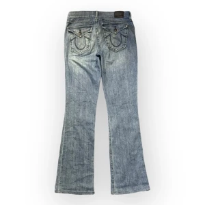 lågmidjde bootcut true religion jeans - jättefina true religion jeans. dem är lågmidjade och flared. midjemåttet rakt över är ungefär 35cm . ytterbenet är 99cm och innerbenslöngden är 74cm