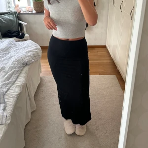 Maxi kjol - Fin lång svart kjol med en slits där bak från Nelly! Ett stygn av sliten längst ner har gått upp (se sista bilden) men är knappt märkbart när man har den på & är nog lätt att fixa! Är 172 cm lång!