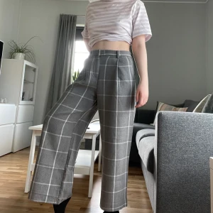 Gråa byxor från Monki - Säljer rutiga gråa byxor från monki. På det högra byxbenet har sömmen längst ner gått upp. Annars gott skick och måttligt använda. Säljs för 50 kr. 