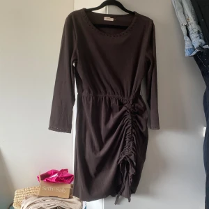 Fin mocca klänning - Snygg mocca klänning i mörkbrun färg, strl 36 , har sytt in en ruffel effekt på vänster kjol sida (se bild) som man kan justera beroende på hur mycket ruffel du vill ha men om man ej vill ha den så kan man dra bort lädersnöret 