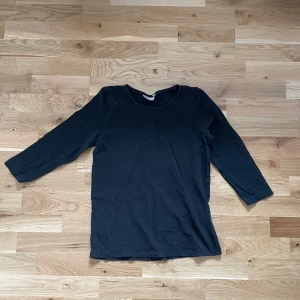 Svart tröja med 3/4 ärmar  - Säljer en helt vanlig svart tröja med 3/4 ärmar. Måttligt använd men i gott skick. Säljs för 20 kr. 