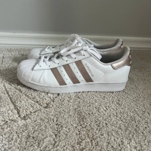 Adidas superstar vit/guld - Super söta Vita Adidas skor med guld detaljer💓. Använda 1-2 ggr. St 39-40, priset går att diskutera☺️