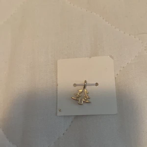 Guldörhänge med julgransmotiv - Ett guldörhänge i form av en julgran. Perfekt för att fira julen med stil.