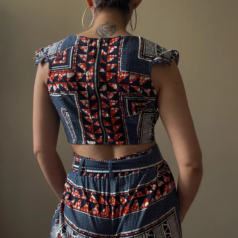 Beautiful wax print set in navy and orange colors. Handcrafted Top features a unique cap sleeve and crop boxy silhouette. Back Zip Closure. Matching Pants Sold Separately  100% Cotton  Best Fits Size XS. Blusar.