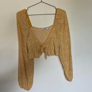 Crop topp - Gul croptop med vita blommor. Knyts framtill. Fint skick! 