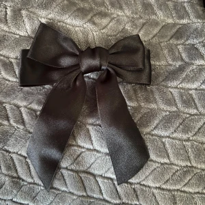 Svart diadem med rosett - Ett elegant svart stor rosett. Perfekt för att ge en extra touch till din outfit.