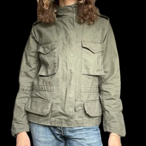 Militärgrön jacka  - Så cool militärgrön jacka med coola detaljer som dragkedja vid kragen, i fint skick. Storlek M. 