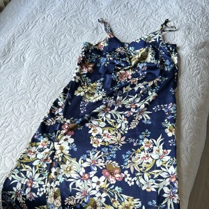 En somrig silkes klänning! - En fin sommar klänning med slit på sidan. Den har även knappar på sidan som detaljering, banden går även att justeras. Har aldrig använt den då den inte passar mig. Jag är 154 cm och den når precis under fötterna.  Pris går att diskuteras!💕🌸🌸