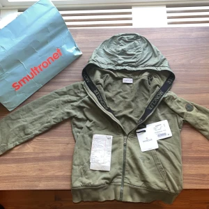 Hooded Moncler cardigan - Säljer denna Moncler cardigan/kofta i färg mörkgrön. Storleken är 14A,(164). Förutom att det finns ett litet hål o vänster ficka som är fixat så är den i bra skick. Nypris är 3200kr. Tar annars byten i samma prisklassen. Hör av dig vid frågor.