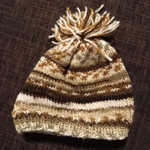 Brunglittrig mössa strl. 44 - Stickad tunnare vårmössa i bruna toner med inslag av glitter i ca storlek 44 (se storleksjämförelse med mössa på bild 4-5). Oanvänd, endast upptvättad. Unisex   Tvättad i parfymfritt tvättmedel och utan sköljmedel.