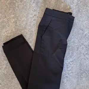 Svarta kostymbyxor från H&M med liten slits i benen  Stängning med hake och knapp  2 fickor fram och 1 höger bak