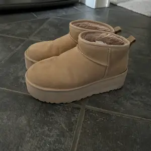 UGG Boot 'Classic Ultra' i Ljusbrun Använt skick.  Har en mörkade fläck på vänstra skon (se bild)  Storlek 41, förutom en mörkare fläck inga defekter.