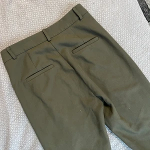 Kostymbyxor mörkgröna  - Byxor från Chiquelle: Mörkgröna kostymbyxor. Märke Dilvin. Storlek 38. Uppsydda för någon som är runt 165 cm lång. Sparsamt använda. Obs ganska liten medium.
