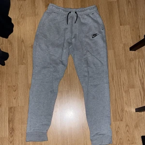 Gråa Nike Tech byxor  - Knappt använda gråa Nike Tech byxor köpte för ungefär ett halvår sen, säljer byxorna för de inte kommer till användning.