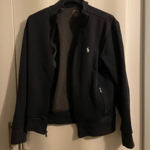 Polo Ralph Lauren full zip ( utan luva ) - Hej säljer nu denna full zipen från Ralph Lauren | Nyskick INGA TECKEN PÅ ANVÄNDNING 🤩| Självklart äkta och om man är intreserad kan jag fixa kvitto/ äktahetsbevis | Nypris: 1799kr| Vid eventuella frågor eller funderingar är det bara att höra av sig🤩