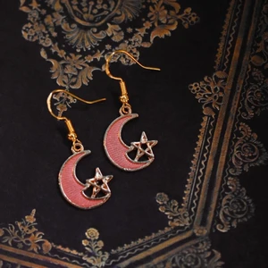 Örhängen med rosa månar - Handgjorda örhängen med guldpläterad berlock och nickelfria krokar 🌙 På min profil finns fler örhängen med berlocker i flera andra storlekar, färger och former! 🪐 Köp 1 par för 40kr, 2 par för 70kr, 3 par för 100kr! Örhängena levereras i en fin liten presentpåse. Frakt på 13kr tillkommer 💫