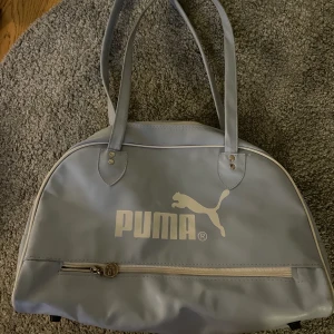 Puma väska  - Säljer en blå Puma väska då den inte kommer så bra till användning. Väskan är rymlig och lätt att använda. Köpt på secondhand. Se rättvisare färg på sista bild. 140kr+frakt. Buda i kommentarerna.