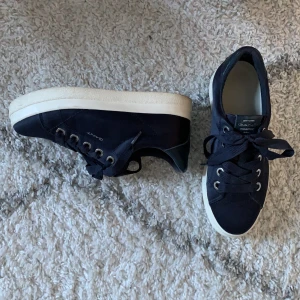 GANT sneakers - Säljer mina superfina gant sneakers då de endast använts 2 gånger! De är marinblåa och lite silkesskimriga, super fräscha till vitt!  De är i storlek 38 och är köpta på väla i Helsingborg. Nypris:999kr Jag säljer dem nytvättade för 449kr då de knappt är använda och inga skador eller skavanker finns! Hör av er för fler bilder☺️