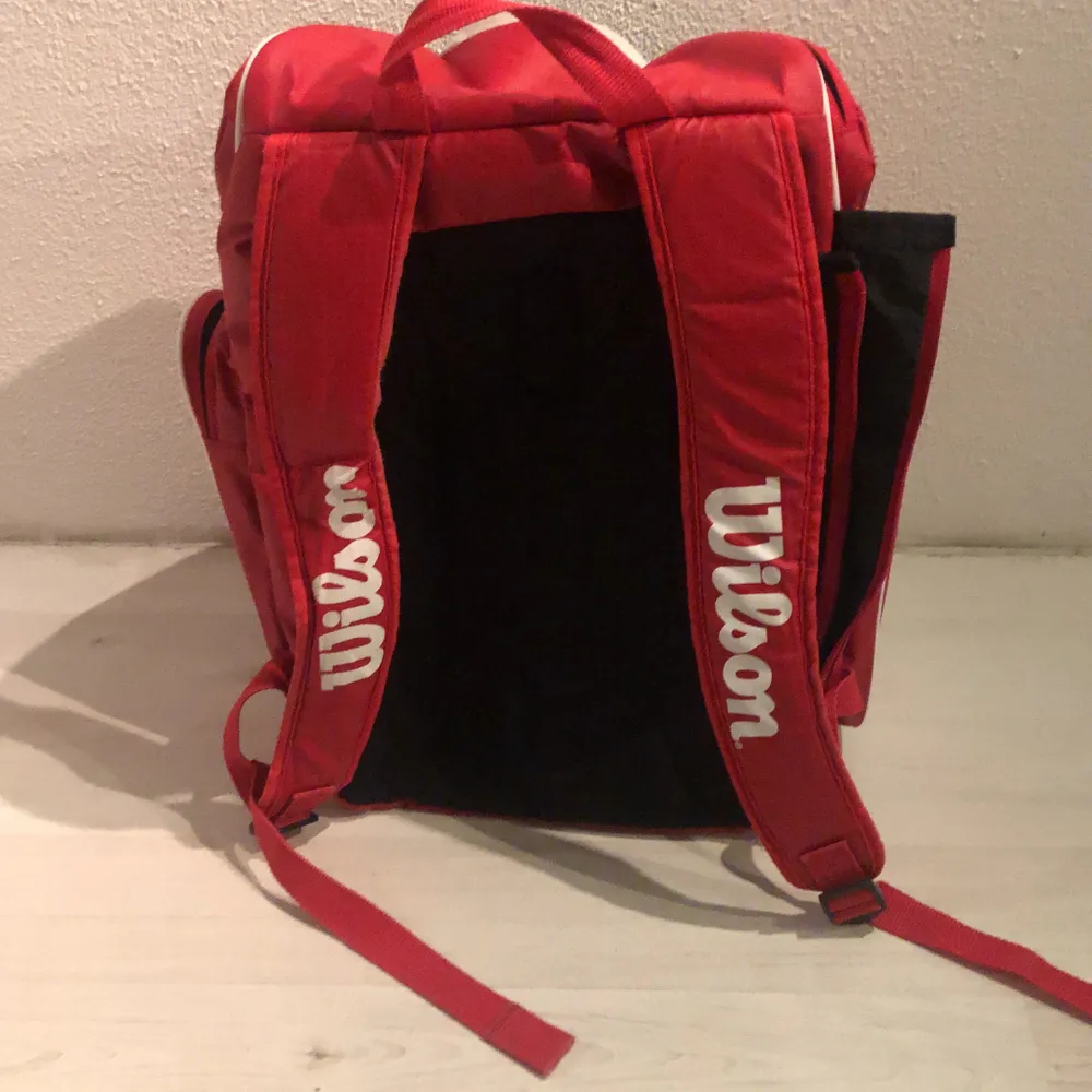 En röd wilson tennis väska med 8 fack. Säljer eftersom har köpt en större och ett annat märke.. Väskor.