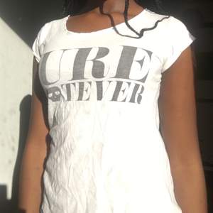 En typisk vit t-shirt med trycker ”Sure Whatever” med en döskalle istället för A. T-shirten är från Sally&Circle. Använd ett flertal gånger.