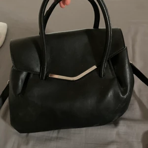 En svart handväska - En svart handväska. Kommer inte ihåg var den är köpt då den är rätt gammal men aldrig kommit till användning.
