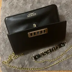 Classy evening handbag, colour black with golden chain strap and golden details. Size:7’’x4’’x5”. It has 6 different pockets, one of them with Zippers. Brand: Guess