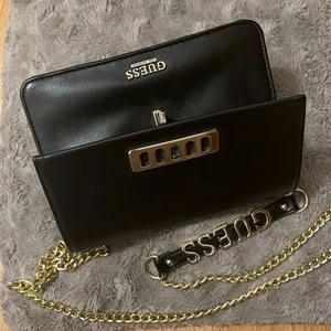 Guess black evening bag - Classy evening handbag, colour black with golden chain strap and golden details. Size:7’’x4’’x5”. It has 6 different pockets, one of them with Zippers. Brand: Guess