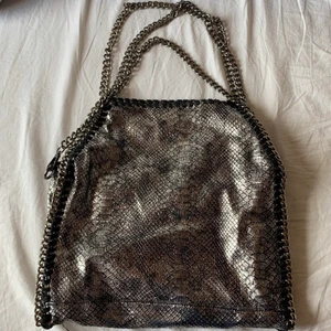 En Stella McCartney liknade väska  - !!Intressekoll!!En superfin mörkgrå/silvrig skimrig stella mccartney liknande väska med dragkedja och två olika längder på kedja. Inuti är den röd! Buda i kommentarerna! vid frågor och flera bilder är det bara att skriva till mig. Vid bra bud så säljer jag den💓(KÖPAREN STÅR FÖR FRAKT!)