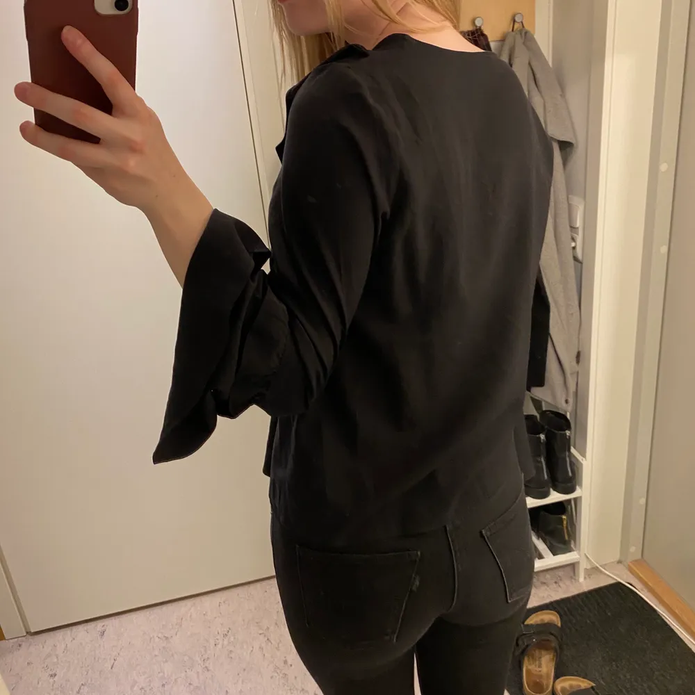 Blus i mycket fint skick, som oanvänd! Volanger framtill och vida ärmar. Puserot.