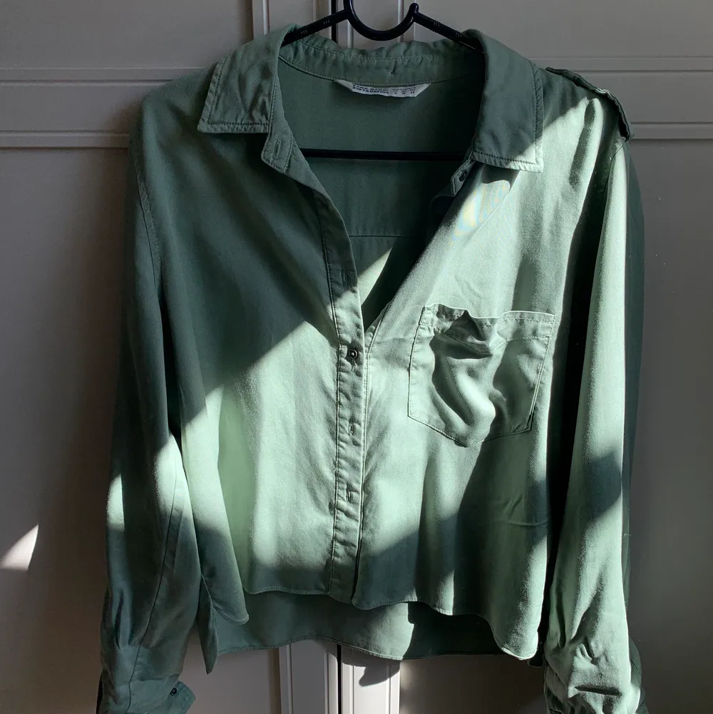 Säljer denna croppade gröna skjortan som är super fräsch nu till våren! Den är militärgrön med en ficka på ena bröstet. Säljer för 150 kr ink frakt! . Skjortor.
