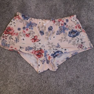 Ljusrosa pyjamas shorts  - Grisrosa pyjamas shorts med blå och röda blommor på ifrån lindex. Väldigt stretchiga med resor i midjan. Knappt använda. Storlek: small
