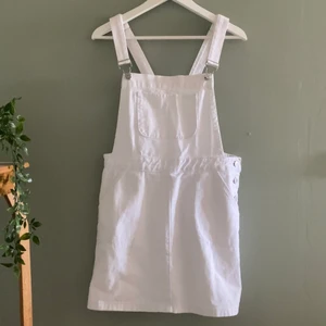 Vit jeansklänning med silvriga spännen  - En vit jeansklänning med silvriga spännen, köpt på en butik i Spanien. Använd en gång men då lyckades jag såklart få två fläckar på den som tyvärr inte går bort i tvätten (se bild). Den ena sitter på baksidan på nedersta delen på kjolen och sen andra sitter på insidan av framsidan.