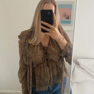Leopardmönstrad Blus från Zara - Leopardmönstrad blus från Zara med resår i midjan och ”slips” som kan knytas eller hänga löst (som på bilden). Använd ett fåtal gånger, resåröglan till knappen högst upp har gått av men kan lätt sys fast igen! Storlek L, jag är 175 cm för referens.