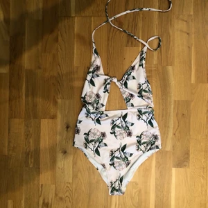 Blommig baddräkt från H&M - Blommig ljusrosa baddräkt från H&M. Jättefin med Cut out under bröstet. Knytes i nacken och djup rygg. Storlek 36. Säljer för 100kr. Fraktas för ytterligare 66kr. 🍓☀️