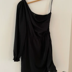 Klänning  - Den perfekta nyårsklänningen! Aldrig använd utan bara testad. Strl 38. Snygga detaljer med snörning på ena sidan. Dragkedja vid ena revbenet. Glansigt material. Nypris 399kr. 